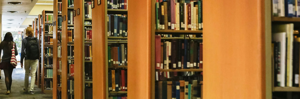 Two students walking through stacks